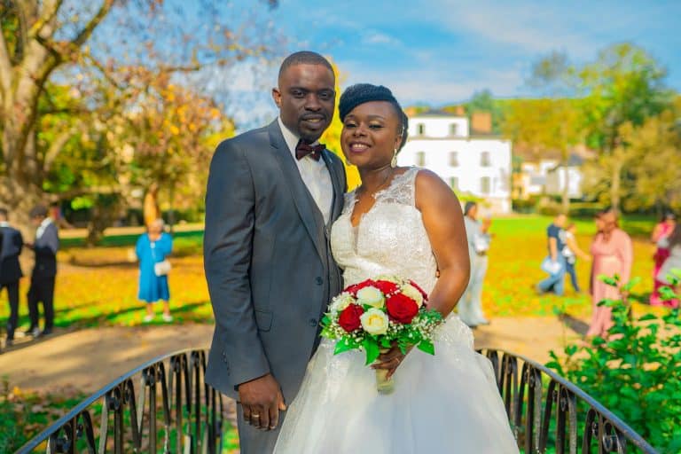 A joyful couple posing outdoors on their wedding day in Paris, surrounded by nature and friends.