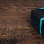 A stylish black gift box with blue ribbon on a wooden table, perfect for celebrations.