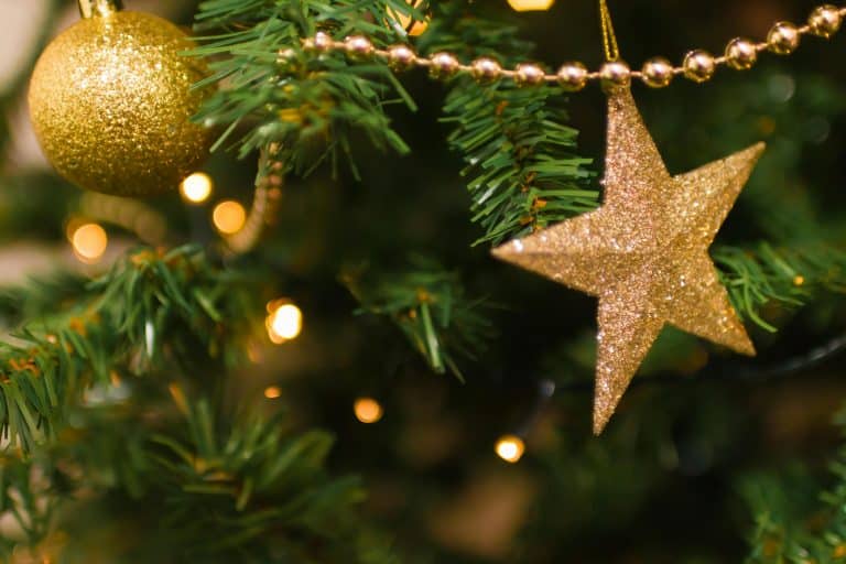 Close-up of a Christmas tree with golden star and ornament, shimmering lights and festive decorations.